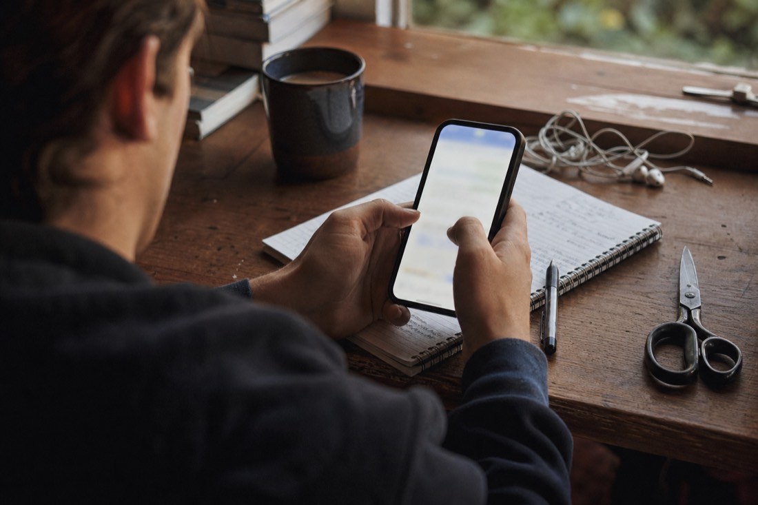 Hands holding a phone above a desk