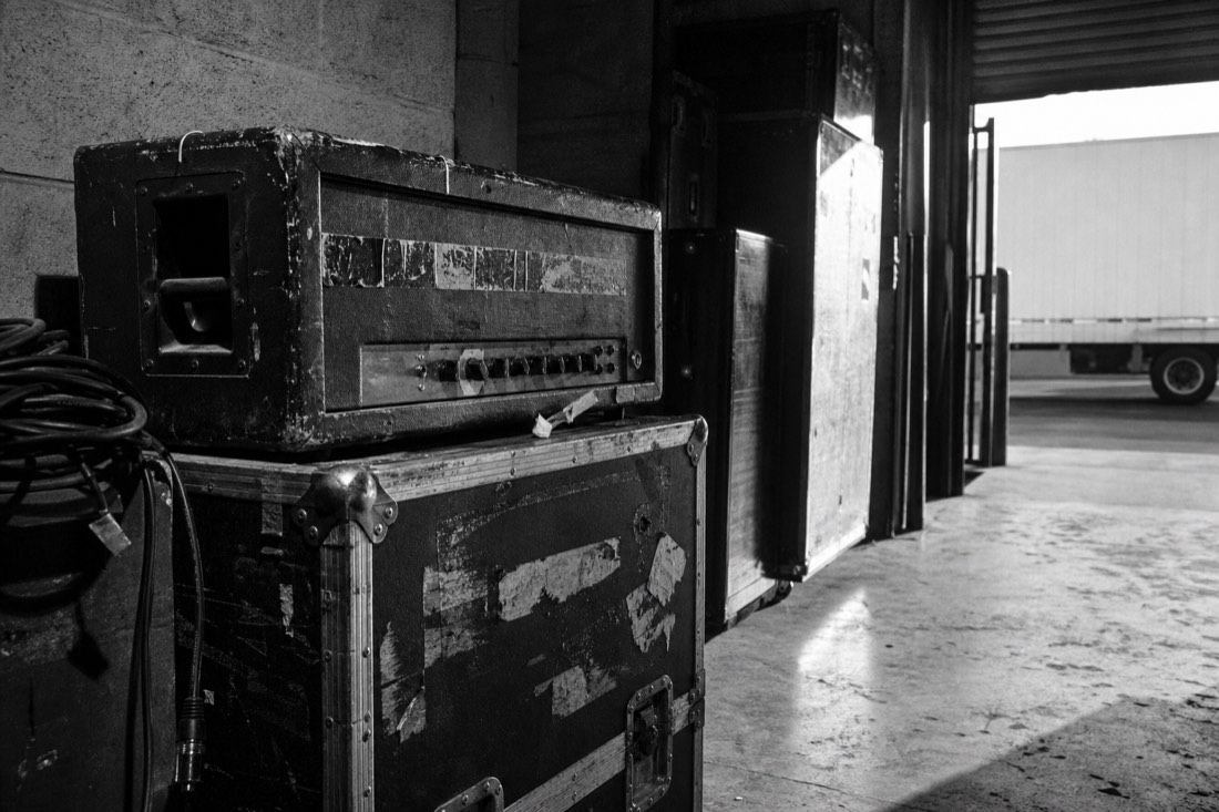Battered flight cases and an amp head in a loading bay