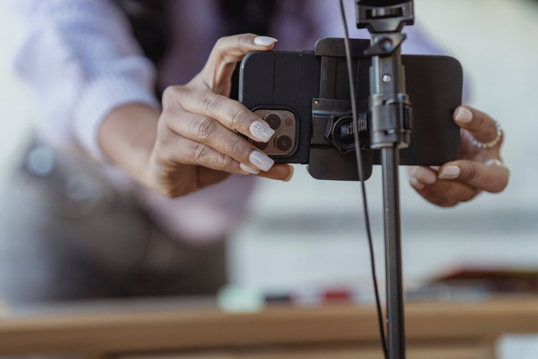 Hands fitting a phone into a clamp on a tripod